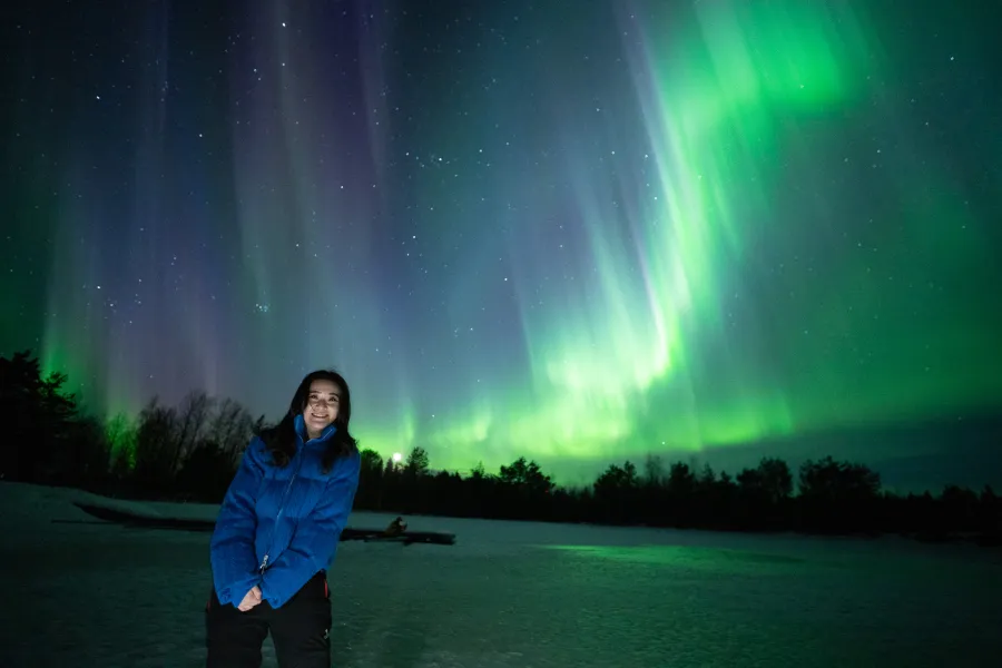 Guest in a blue jacket under a wide green aurora
