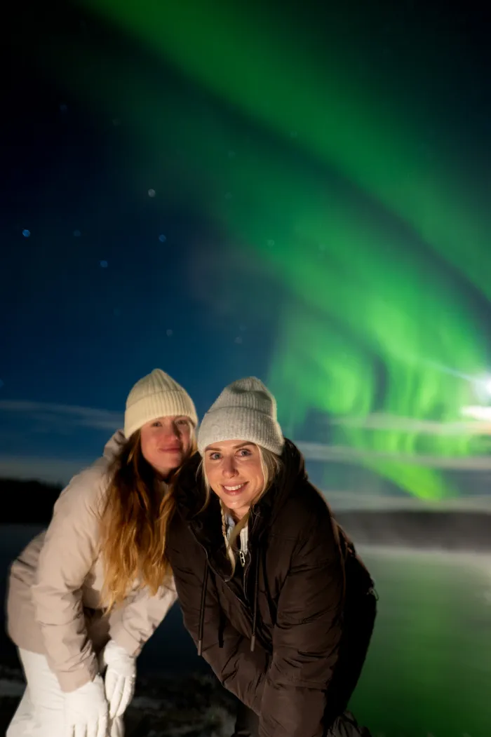 Two guests under a sweeping green aurora