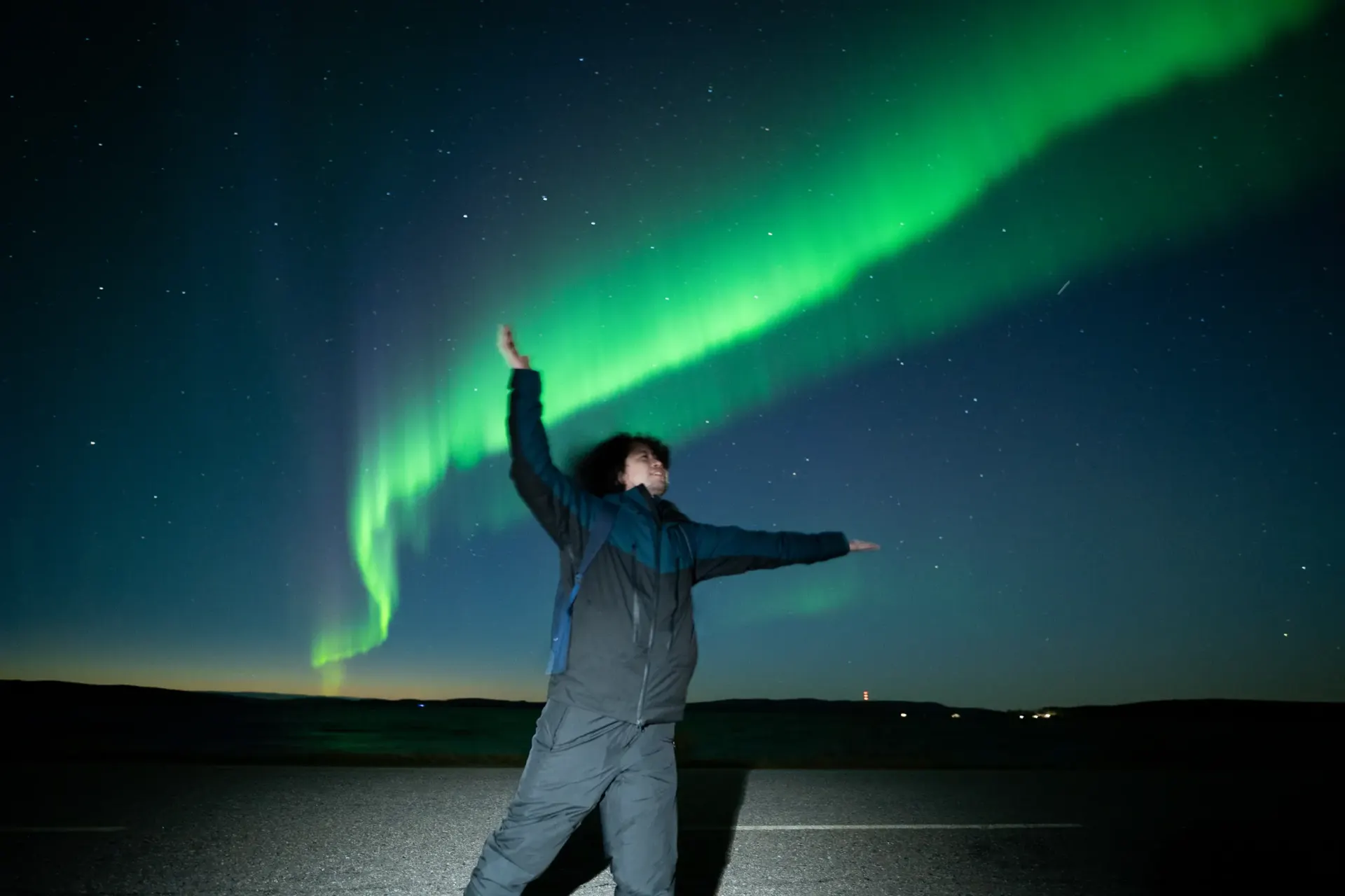 Guest celebrating under a wide aurora arc on a private Lapland tour