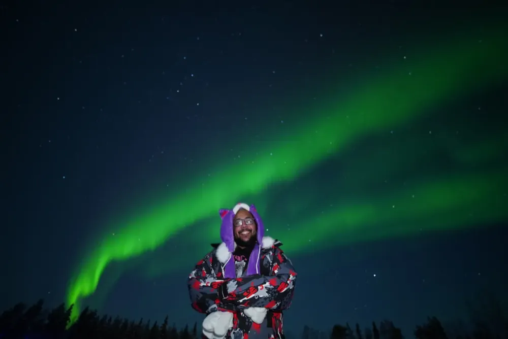 Smiling tour guest beneath the Northern Lights