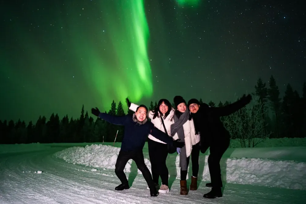 Group of guests jumping for joy under the Northern Lights