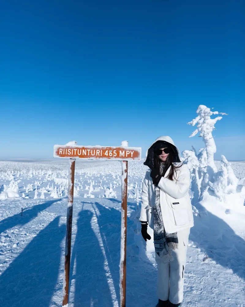 Guest at the Riisitunturi summit sign, 465 metres above sea level, surrounded by snow-crowned tykky trees