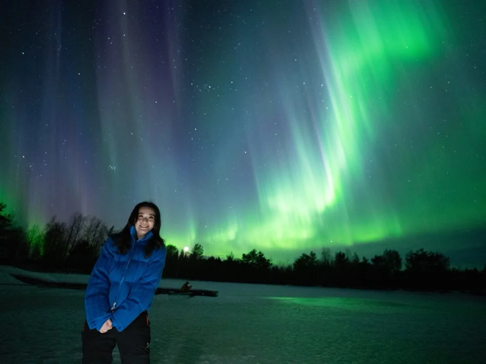 Smiling guest under a vivid green aurora on a small-group Experience Tours hunt